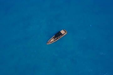 Lonely boat mooring on the water. luxury motor boat. Drone view of a boat. Top view of a white boat in the blue sea. Aerial view of a yacht on blue water.