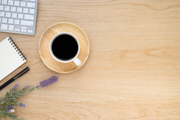 Top view above of Wooden office desk table with keyboard, notebook and coffee cup with equipment other office supplies. Business and finance concept. Workplace, Flat lay with blank copy space.