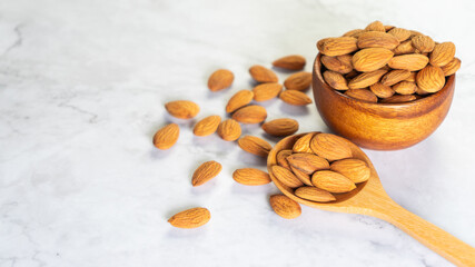 Almonds in wooden bowl with wooden spoon on the table.Healthy food Concept.