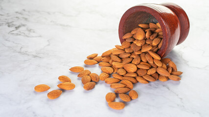 Almonds pour from wooden bowl on the table.Healthy food Concept.
