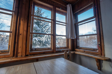 Cozy breakfast in a cabin with a window on nature, with a snowy landscape in the background, working from home, holidays and dexterity from the city, in the countryside.