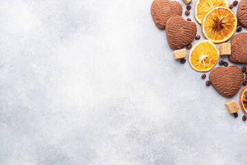 Chocolate heart cookies, oranges cinnamon and spicy spices on a gray table, top view, copy space.