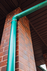 Plastic green drainage pipe on the wall of the house to drain water from the roof into the ground