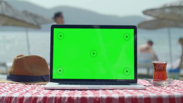 Women use a green screen computer on the beach. The concept of working on the summer beach.