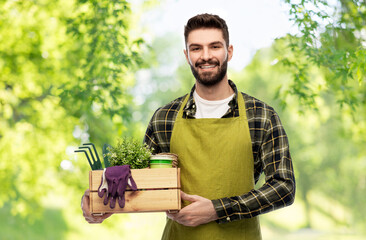 gardening, farming and people concept - happy smiling male gardener or farmer in apron with box of...