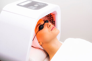 Express facial treatment with led therapy. Beautiful girl on a light therapy procedure. LED lamp...