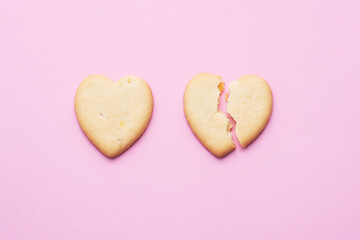 Heart shaped cookies, a cracked heart on a pink background, the concept of a broken relationship.