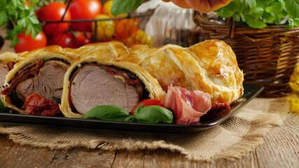 Baked sirloin in puff pastry. Sliced pieces, served with sun-dried tomatoes, salad, and olives. Decorate with a basil leaf.