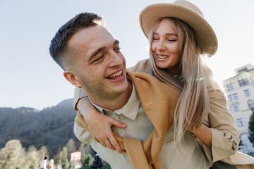 Close up portrait of happy romantic couple having fun and laughing outside, love story on valentine's day, man carries woman on his back