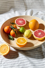 Obraz na płótnie Canvas food, healthy eating and vegetarian concept - close up of citrus fruits on wooden plate