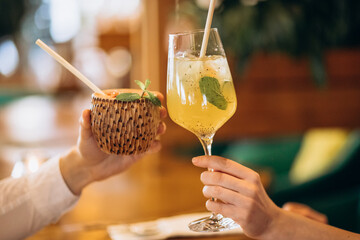 Close up image of woman and man holding delicious fresh lemonade cocktail and juice. Two cocktail glasses of tasty tropical cocktails  in the hand of a man and a woman - 404788924