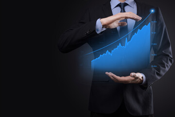 Business man holding holographic graphs and stock market statistics gain profits. Concept of growth planning and business strategy. Display of good economy form digital screen.