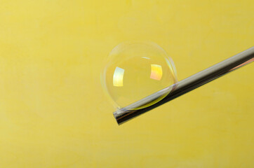 Blowing bubble stick and bubble on it against yellow background