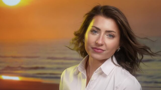 Attractice Caucasian woman on beach at sunset with hair blowing in the wind in slow motion close up