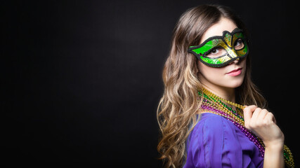Mardi gras party, masquerade. Woman with a carnival mask and beads on the black background with...