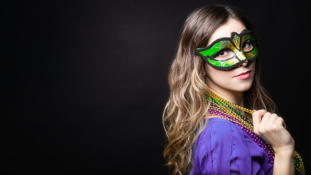 Mardi gras party, masquerade. Woman with a carnival mask and beads on the black background with copy space, banner