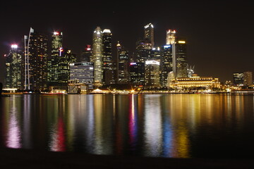 Fototapeta na wymiar Illuminated Buildings By River Against Sky At Night