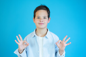 Boy showing okay gesture in sign language on blue background