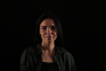 Portrait of beautiful young brunette woman on black background