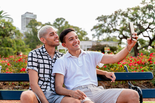 Young gay couple taking selfies a public park