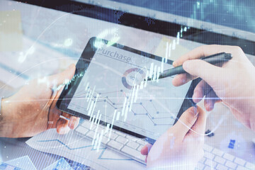 Double exposure of man's hands holding and using a phone and financial chart drawing. Market analysis concept.