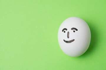Fototapeta na wymiar Egg on green background with joyful contented emotion on face