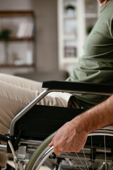 Close up of man holding wheel of wheelchair. Young disabled man in a wheelchair..