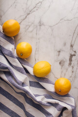 Lemons on a blue and white striped fabric against white marble background. Creative fruit concept.