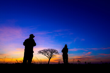 silhouetted people on open field sunset
