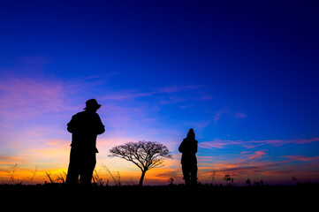Fototapeta premium silhouetted people on open field sunset