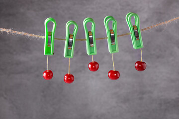 Ripe red cherries on a rope are secured with clothespins