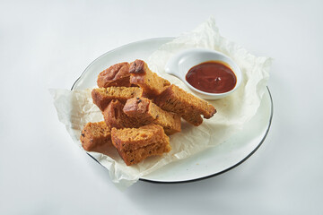 Classic beer snack - rye croutons with garlic and red sauce in a white plate on a white background