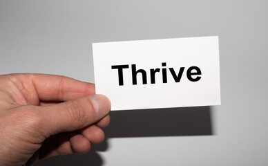 Message on the card THRIVE in hands of businessman.