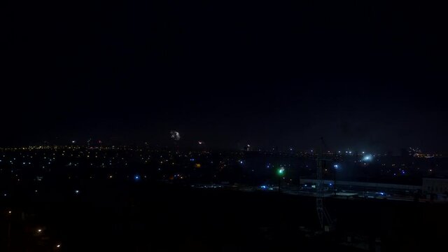 The view from a high point in the city to the many fireworks during the holiday. The night sky is illuminated by flashes of fireworks.
