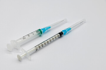Medical syringes and needles for hypodermic injection on a marble counter top. The syringe and needle are capped.