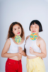 Asian women wearing white vest holding rainbow candy lollipop isolate on white background.