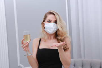 Beautiful blonde in a face mask, holding a glass of champagne.