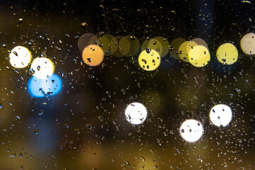 Glass with water drops with an unfocused urban background by night