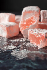 View of Turkish Delight made from roses with sugar on blue marble, selective focus, vertical, with copy space