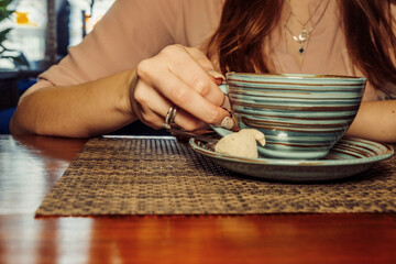 Cup of coffee on a wooden table, the girl holds her hand one cup of coffee . A photo depicting a melancholic mood