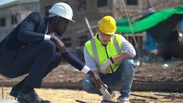 asian foreman and african american architect  checking steel structure road outdoors on construction site at village . contractor worker Inspection and correction rebar steel cage . quality control