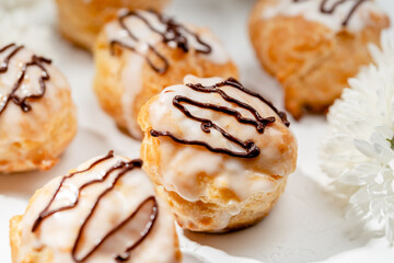 Profiteroles filled with custard on white table
