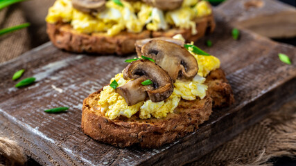 scrambled eggs on rustic toast with mushrooms. healthy breakfast or brunch. Food recipe background. Close up