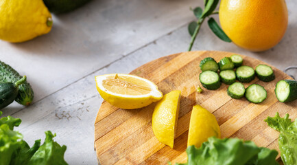 Fresh lemon and cucumber cut into slices on cutting board