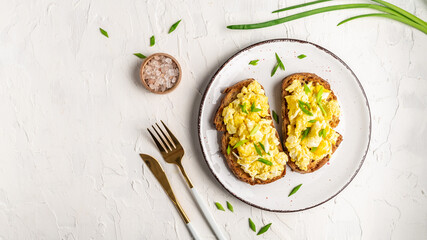 Scrambled eggs with green onion on wheat rye wholemeal crispy bread, homemade, healthy breakfast or brunch. Homemade meal, banner, menu recipe place for text, top view