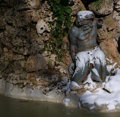 Fototapeta na wymiar Estatua de tritón con nieve y hielo en una fuente
