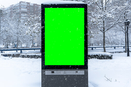 Vertical mock-up of city poster winter city with thick edges, green billboard in urban settings, empty street information placeholder on sidewalk with copy space for logo, advertising