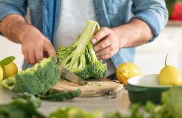 Man preparing delicious and healthy dinner of broccoli at home kitchen