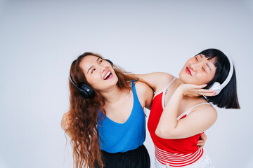 Fototapeta na wymiar Portrait of two asian women enjoy listen to music and dance isolated on white background.