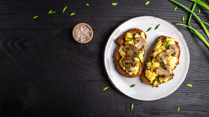 Scrambled eggs with green onion on wheat rye wholemeal crispy bread, homemade, healthy breakfast or brunch. Homemade meal, banner, menu recipe place for text, top view